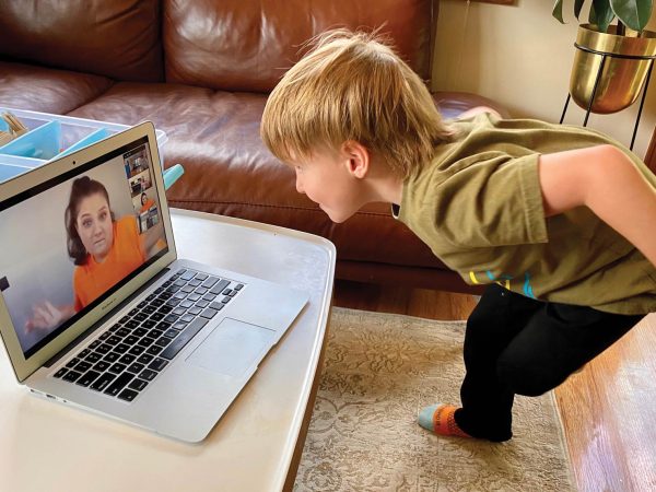 engaging with a woman on a video call. The room has a brown sofa and a patterned rug
