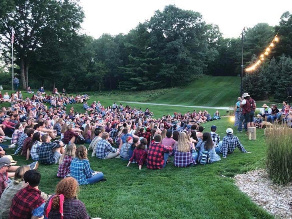 many wearing plaid shirts. String lights hang overhead
