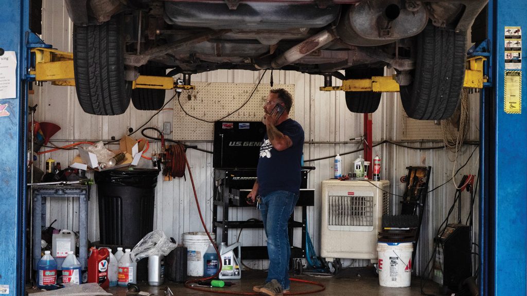 Tuning Spot owner on the phone in his garage with a car up on the lift