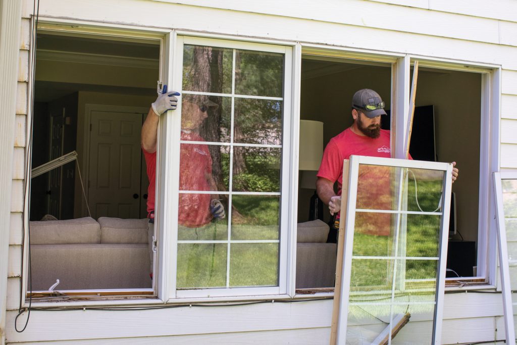 two men removing a window from a building