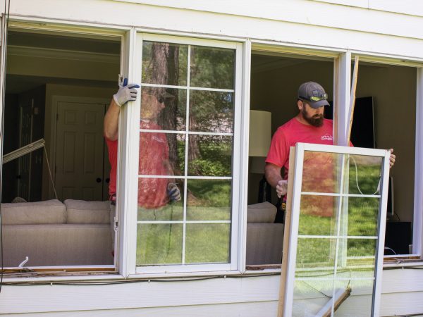 two men removing a window from a building
