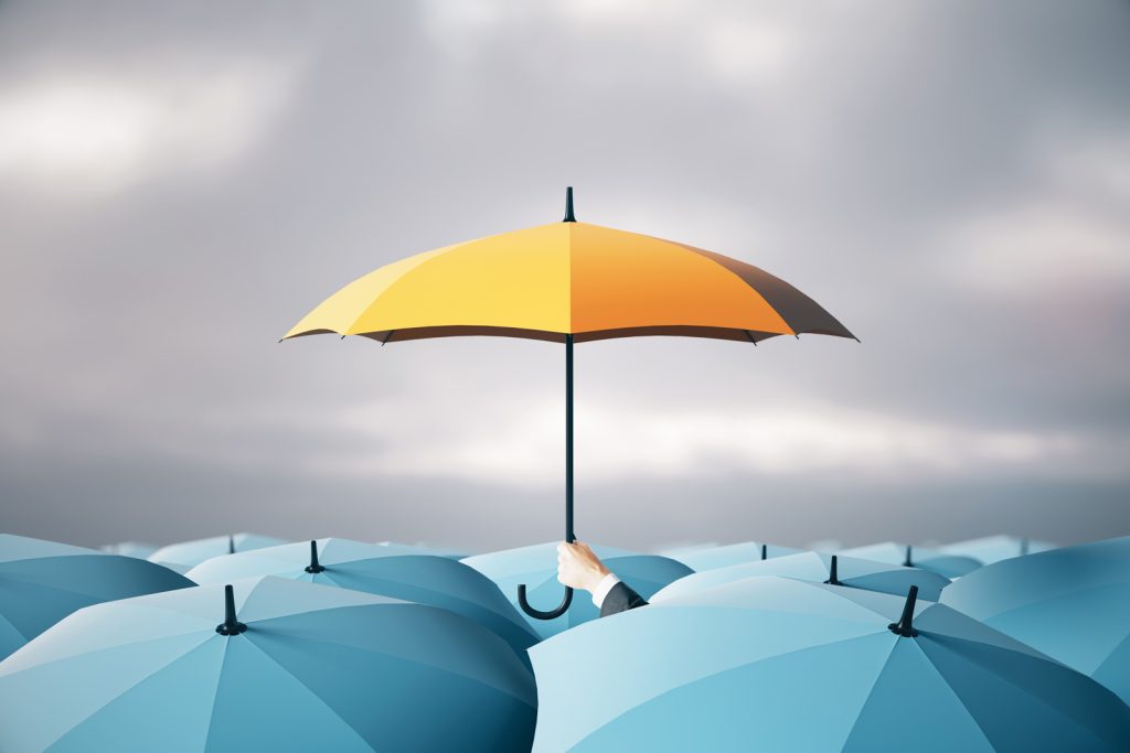 several open blue umbrellas with a hand holding a yellow umbrella above the rest