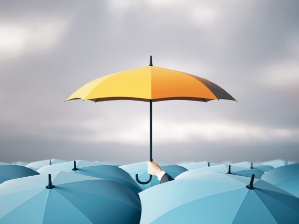 several open blue umbrellas with a hand holding a yellow umbrella above the rest