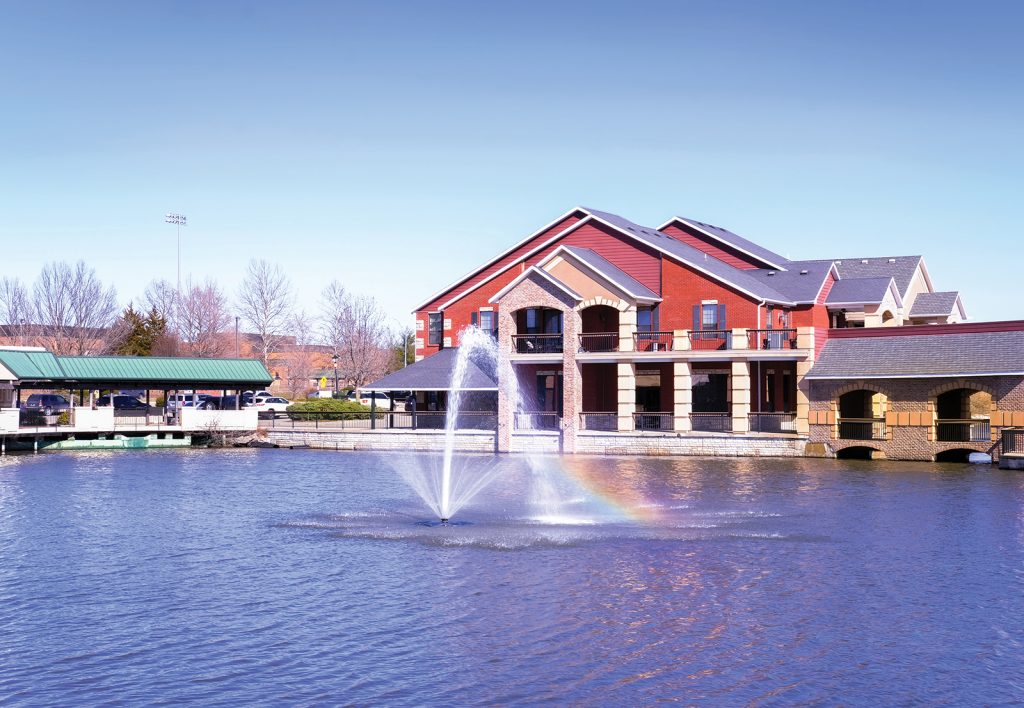 building with pond and fountain in a Midwestern town on sunny winter day; water of the fountain creates rainbow