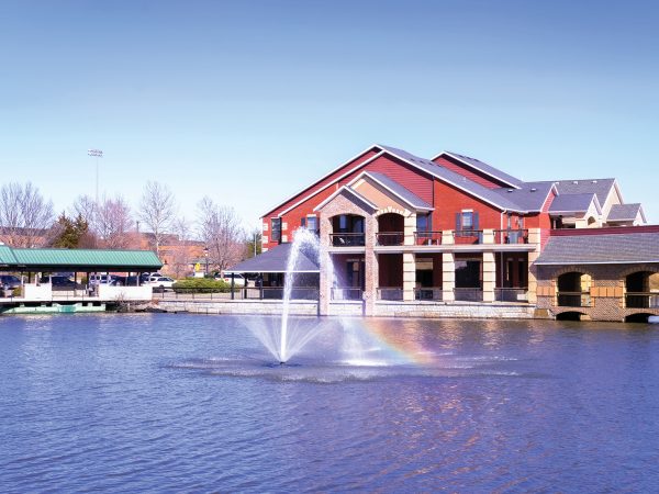 building with pond and fountain in a Midwestern town on sunny winter day; water of the fountain creates rainbow