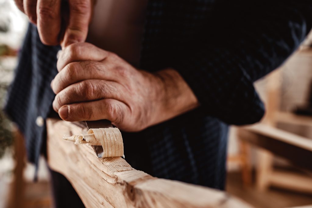 Hands of a carpenter working with chisel and hammer